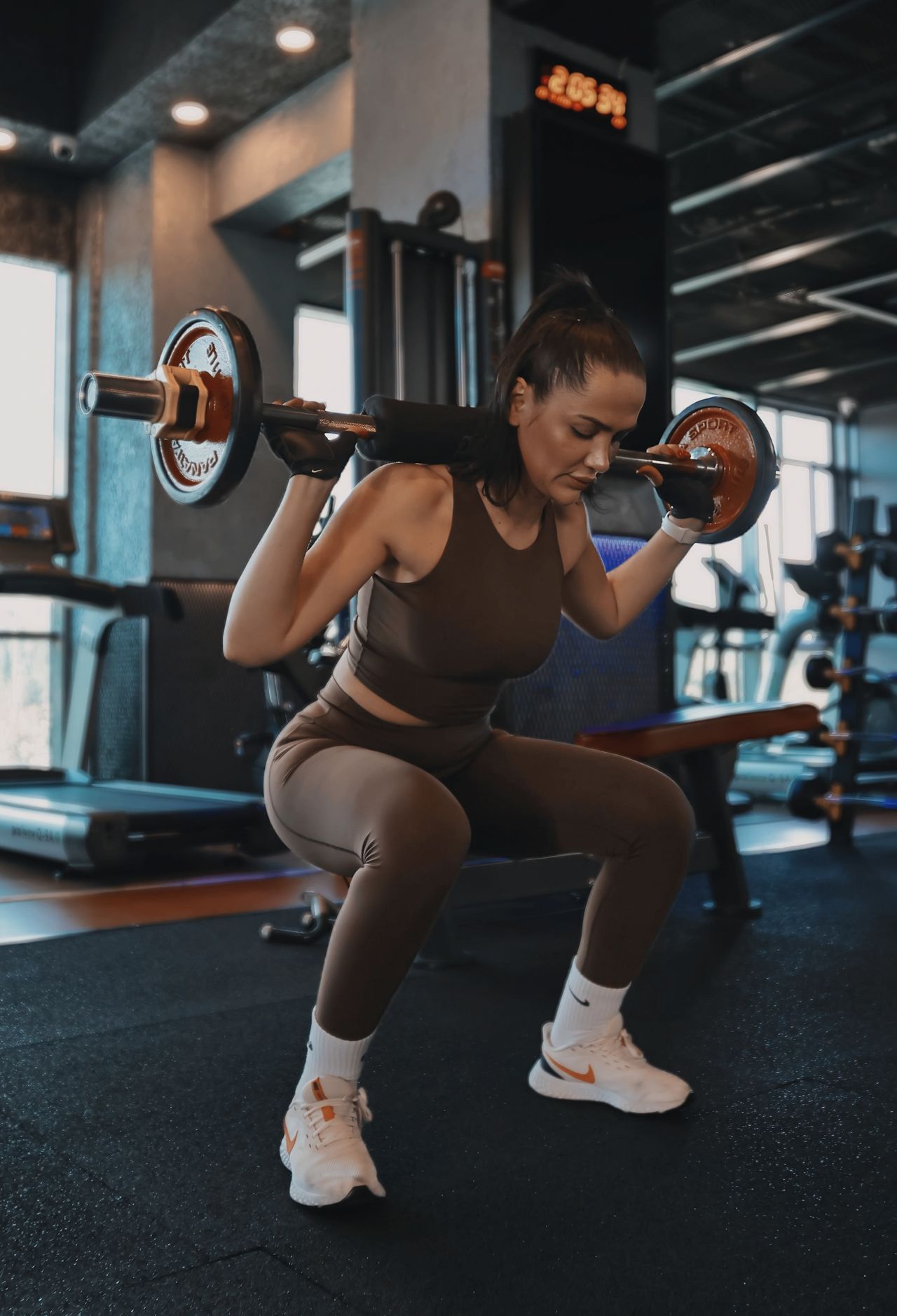 Woman performing a barbell back squat in the gym